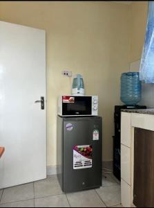 a refrigerator in a kitchen with a microwave on top of it at Olive Homes Thika Town in Thika