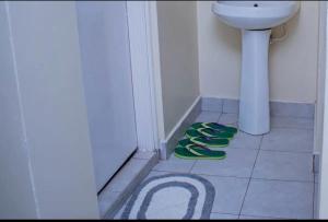a bathroom with green slippers on the floor next to a toilet at Olive Homes Thika Town in Thika +7 photos