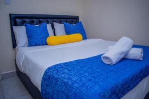 a large bed with blue and yellow pillows on it at Olive Homes Thika Town in Thika