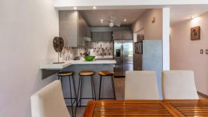 una cucina con sedie bianche e tavolo in legno di Elegant Condo with Brand-New Fixtures, Shaded Tropical Terrace, and Secluded Beach Access a Playa Flamingo