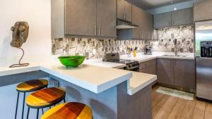una cucina con bancone e due sgabelli di Elegant Condo with Brand-New Fixtures, Shaded Tropical Terrace, and Secluded Beach Access a Playa Flamingo Altre 20 foto