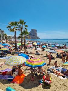 a crowd of people on a beach with umbrellas at Ap Skerup Calpe City cerca Playa in Calpe