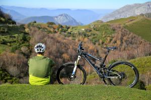 a man sitting on a hill with a bike at El Torreón - Las Casas del Oso in Proaza