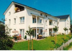 a large white house with people sitting outside of it at Haus Bernstein Ferienwohnungen in Göhren
