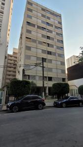 two cars parked in front of a large building at Quarto e banheiro privativos no Jardins in São Paulo