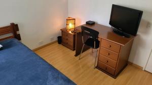 a bedroom with a bed and a dresser with a television at Quarto e banheiro privativos no Jardins in São Paulo