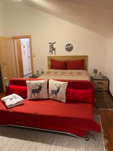 a bedroom with a red bed with two deer pillows at Villa Alessandra in Colle Isarco