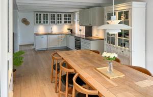 a large kitchen with a wooden table and chairs at Beautiful Home In Blåvand With Sauna in Blåvand +24 photos
