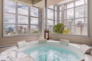 a large bath tub in a room with windows at Trend Nova Carlos Gomes - 406 in Porto Alegre