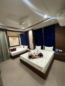 two beds in a room with blue curtains at HOTEL PREMIER CHOICE - JUST 50 Meters FROM AJMER SHARIF DARGAH in Ajmer