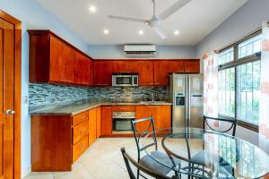 a kitchen with wooden cabinets and a glass table at 2 Bedroom Ocean-View Condo with Pool in Playa Flamingo