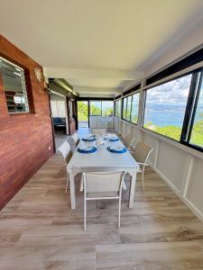 una sala da pranzo con tavolo, sedie e finestre di La villa Azur classée 3 étoiles Moderne et Confortable à deux pas de la plage de l Anse à l Ane Trois Îlets - Service Petit Dej sur demande a Les Trois-Îlets