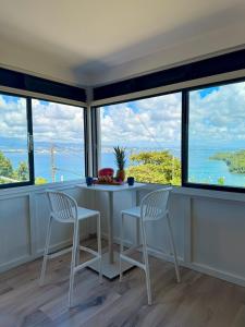 a kitchen with two chairs and a table and windows at La villa Azur classée 3 étoiles Moderne et Confortable à deux pas de la plage de l Anse à l Ane Trois Îlets - Services Petit Dej sur demande in Les Trois-Îlets