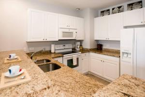 a kitchen with marble counter tops and white cabinets at Elegant 2-BD Condo with Pool in Coco
