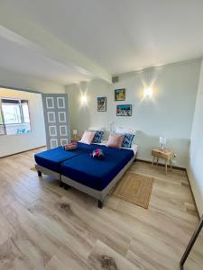 una camera da letto con un letto blu e un pavimento in legno di La villa Azur classée 3 étoiles Moderne et Confortable à deux pas de la plage de l Anse à l Ane Trois Îlets - Service Petit Dej sur demande a Les Trois-Îlets