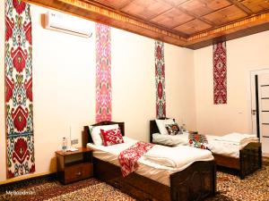 two beds in a room with colorful wallpaper at "Sofia" Guest House in Samarkand
