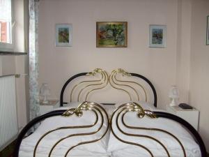 a bedroom with a bed with white sheets and gold accents at Pension Kroth an der Mosel in Briedel