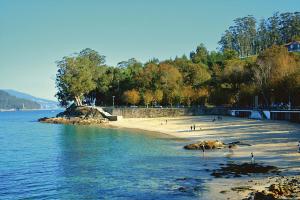 a beach with people on the sand and water at Aguete III in Marín