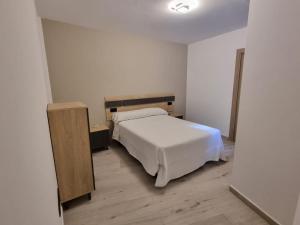 a bedroom with a white bed and a wooden cabinet at Aguete III in Marín