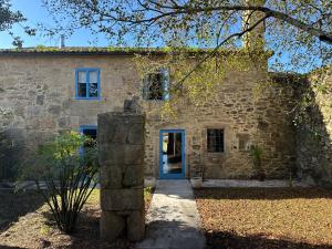 una vieja casa de piedra con una puerta azul en Casa do Bidueiro, en Luou