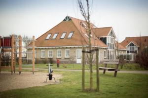 a playground in front of a house with a building at Weidevilla 14 auf Ameland in Hollum