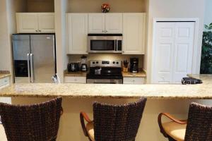 a kitchen with a counter with chairs and a refrigerator at Ground-Floor Unit in Front of Lazy River Pool at Pacifico in Coco in Coco