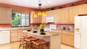 a kitchen with wooden cabinets and a island with bar stools at Spacious One-Bedroom Condo with Pool View, Balcony & Beach Club Access in Coco +33 photos