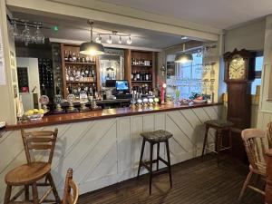 a bar with chairs and a clock in a room at Lord Nelson Hotel in Bridport +3 photos