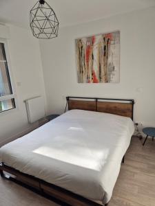 a bedroom with a white bed with a picture on the wall at Résidence de la Brasserie in Saint-Valery-sur-Somme