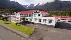 eine Luftansicht eines weißen Gebäudes mit rotem Dach in der Unterkunft Heartland Hotel Fox Glacier in Fox Glacier