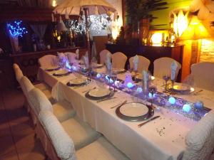 une grande table avec des chaises blanches et des lumières sur celle-ci dans l'établissement Chambres d'hotes La Maison Bleue, à Souvans