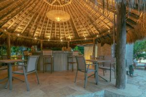 un ristorante con tavoli e sedie sotto un tetto di paglia di Islawa Soy Local - Isla Privada a Barú