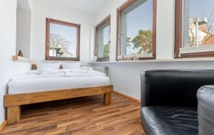 a bedroom with a bed and a couch and windows at Ostseebad-Karlshagen-grosszuegige-Ferienwohnung-Sommer in Ostseebad Karlshagen
