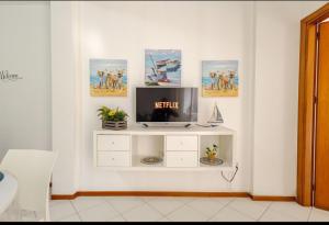 un salon avec une télévision sur un mur blanc dans l'établissement "Stella Home " Perfetto per le tue vacanze in Sicilia sul Golfo di Castellammare ! Relax a pochi mt dal mare per Amici e Famiglie, à Alcamo Marina