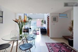 a living room with a glass table and chairs at Duplex Penthouse Zona Rosa in Mexico City