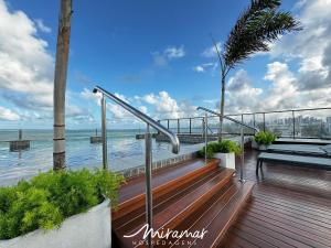 若昂佩索阿Alta Garden- Pé Na Areia-Miramar Hospedagens的木甲板上设有长凳和棕榈树