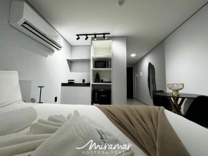 a bedroom with a bed and a table and a kitchen at Alta Garden- Pé Na Areia- MH in João Pessoa
