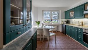 eine Küche mit grünen Schränken und einem Esstisch in der Unterkunft Bernsteinbad Koserow - Haus Fünf Elemente Ferienwohnung Feuer in Ostseebad Koserow
