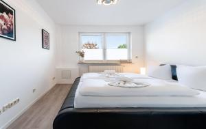 ein Schlafzimmer mit einem großen weißen Bett mit einem Fenster in der Unterkunft Bernsteinbad Koserow - Haus Fünf Elemente Ferienwohnung Feuer in Ostseebad Koserow