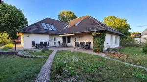 ein weißes Haus mit einem Tisch und Stühlen im Hof in der Unterkunft Bernsteinbad Koserow - Haus Fünf Elemente Ferienwohnung Feuer in Ostseebad Koserow