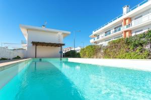 a swimming pool with blue water in front of a building at Host Wise - Serene Spacious House - Swimming Pool & Garden in Olhos de Água
