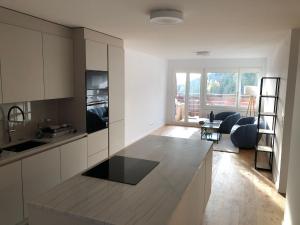 a kitchen with white cabinets and a living room at Bel Appartement Centre Crans Montana, Vue Alpine et Fraîcheur in Crans-Montana
