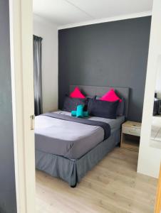 a bedroom with a bed with pink and blue pillows at Cozy corner apartment Muizenberg in Cape Town +45 photos