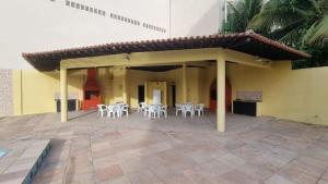a patio with white tables and chairs in a building at Condomínio Bariloche in Salinópolis
