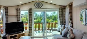 a living room with a couch and a television at Amazing Lodge with Hot Tub in Stowmarket