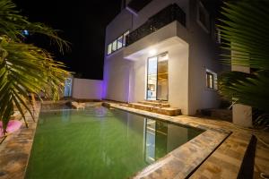 a swimming pool in front of a house at night at Villa serenité lac rose avec cuisinier ,piscine et jacuzzi terrasse vue lac in Ouayembame