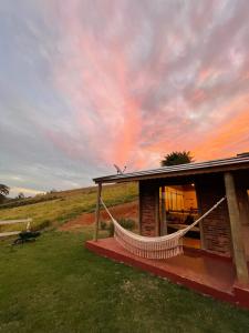 a house with a hammock in front of it at Chalé Cabana Filhos da Terra in Bueno Brandão +18 photos
