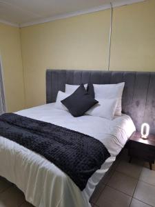 a large bed with black and white sheets and pillows at The Cozy Nook in Piet Retief
