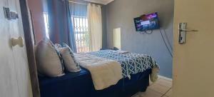 a bedroom with a blue bed with a tv on the wall at St Michael & The Queen in Johannesburg