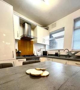 una cucina con tavolo in legno e una cucina con armadietti bianchi di Apartment-Sleeps4-Parking-Balcony a Twickenham